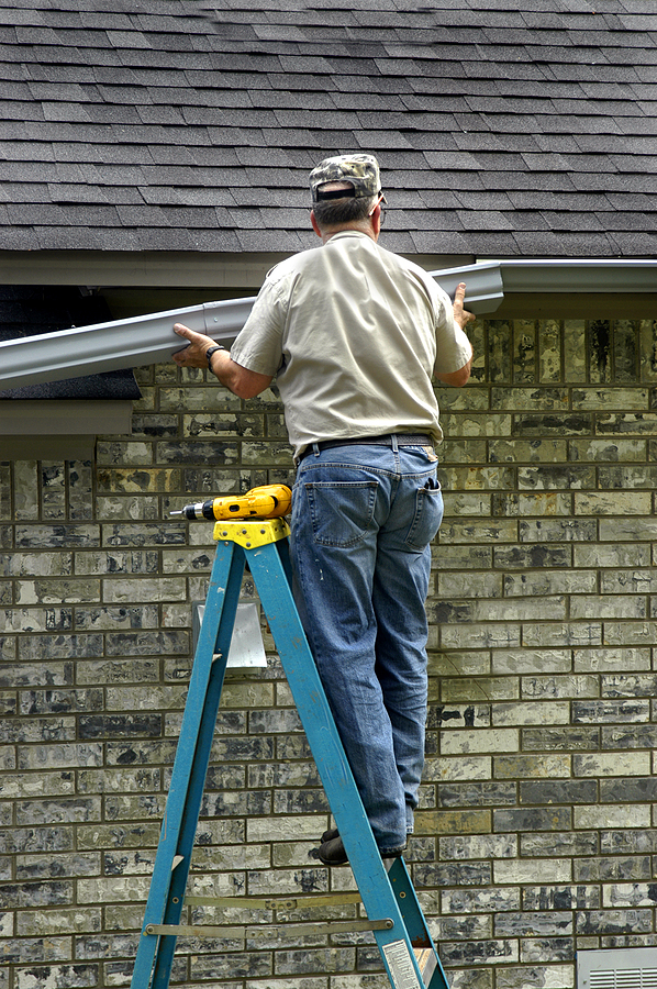 Gutter Job View of brown two story house against blue sky with gables windows and clean roof.