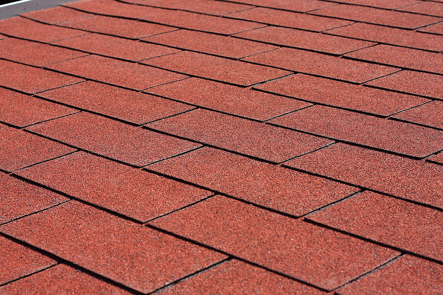 Professionally laid red asphalt shingle rectangular shape on a clean roof Professionally laid red asphalt shingle rectangular shape on a clean roof