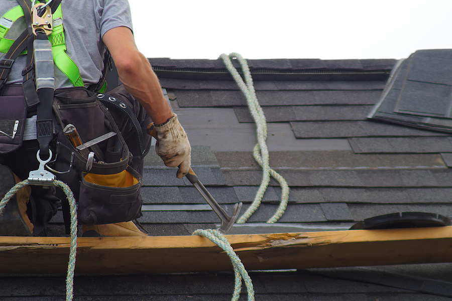 Roofer Construction Roof Repair Rope Security Worker Professionally laid red asphalt shingle rectangular shape on a clean roof
